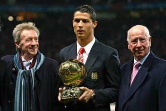 MANCHESTER, UNITED KINGDOM - DECEMBER 10:  Cristiano Ronaldo (C) of Manchester United receives the Ballon d'or as the European Footballer of the Year flanked by previous winners Denis Law (L) and Bobby Charlton before the UEFA Champions League Group E mat