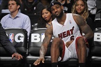 Jan 10, 2014; Brooklyn, NY, USA; Miami Heat small forward LeBron James (6) invites a taunting fan to take a seat next to him during the second overtime against the Brooklyn Nets at Barclays Center. The Brooklyn Nets won the game 104-95 in double overtime.