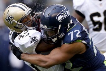 SEATTLE, WA - JANUARY 11:  Running back Darren Sproles #43 of the New Orleans Saints is hit by defensive end Michael Bennett #72 of the Seattle Seahawks in the first half during the NFC Divisional Playoff Game at CenturyLink Field on January 11, 2014 in S