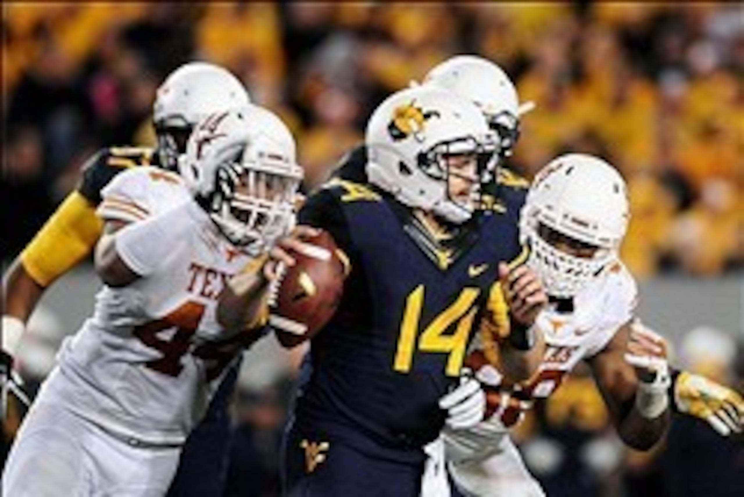 Nov 9, 2013; Morgantown, WV, USA; West Virginia Mountaineers quarterback Paul Millard (14) gets sacked by Texas Longhorns defensive end Jackson Jeffcoat (44) at Milan Puskar Stadium. Mandatory Credit: Evan Habeeb-USA TODAY Sports