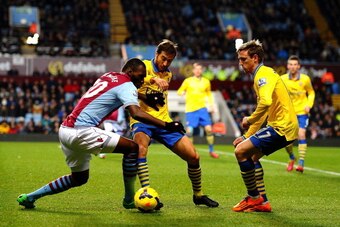 BIRMINGHAM, ENGLAND - JANUARY 13: Christian Benteke of Aston Villa is closed down by Mathieu Flamini and Per Mertesacker of Arsenal during the Barclays Premier League match between Aston Villa and Arsenal at Villa Park on January 13, 2014 in Birmingham, E