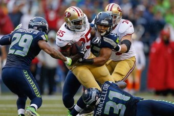 SEATTLE, WA - SEPTEMBER 15:  Tight end Vernon Davis #85 of the San Francisco 49ers is tackled by strong safety Kam Chancellor #31 and linebacker Malcolm Smith #53 of the Seattle Seahawks at CenturyLink Field on September 15, 2013 in Seattle, Washington.  