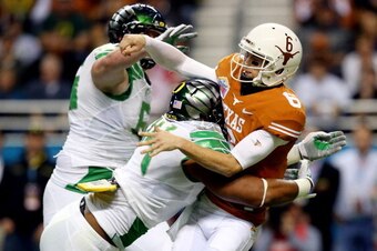 SAN ANTONIO, TX - DECEMBER 30: Quarterback Case McCoy #6 of the Texas Longhorns is tackled by defensive lineman DeForest Buckner #44 of the Oregon Ducks during the Valero Alamo Bowl at the Alamodome on December 30, 2013 in San Antonio, Texas.  (Photo by R
