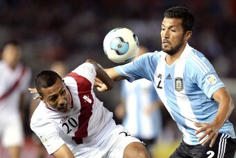 BUENOS AIRES, ARGENTINA - OCTOBER 11: Ezequiel Garay (R) of Argentina vies for the ball with Luis Ramirez of Peru during a match between Argentina and Peru as part of the 17th round of the South American Qualifiers for the FIFA's World Cup Brazil 2014 at 