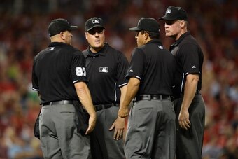 CINCINNATI, OH - AUGUST 23:  The umpires discuss reviewing a home run off the bat of Scooter Gennett (not pictured) of the Milwaukee Brewers in the eighth inning against the Cincinnati Reds at Great American Ball Park on August 23, 2013 in Cincinnati, Ohi