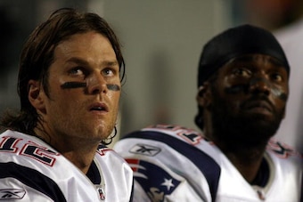 MIAMI - OCTOBER 04:  Quarterback Tom Brady #12 and Randy Moss of the New England Patriots sit on the sidelines  against the Miami Dolphins at Sun Life Stadium on October 4, 2010 in Miami, Florida.  (Photo by Marc Serota/Getty Images)
