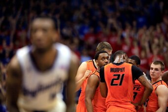 LAWRENCE, KS - JANUARY 18:  Markel Brown #22 and the Oklahoma State Cowboys huddle as Naadir Tharpe #10 of the Kansas Jayhawks shoots a free throw after a technical foul during the game at Allen Fieldhouse on January 18, 2014 in Lawrence, Kansas.  (Photo 