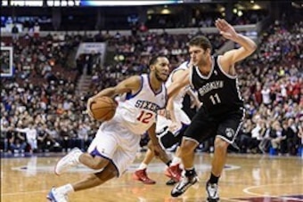 Dec 20, 2013; Philadelphia, PA, USA; Philadelphia 76ers guard Evan Turner (12) is defended by Brooklyn Nets center Brook Lopez (11) during the fourth quarter at the Wells Fargo Center. The Sixers defeated the Nets 121-120 in overtime. Mandatory Credit: Ho