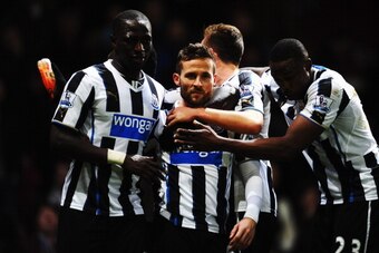 LONDON, ENGLAND - JANUARY 18:  A team mate holds a bottle as Yohan Cabaye (C) of Newcastle United is congratulated by team mates after scoring his sides third goal during the Barclays Premier League match between West Ham United and Newcastle United at th