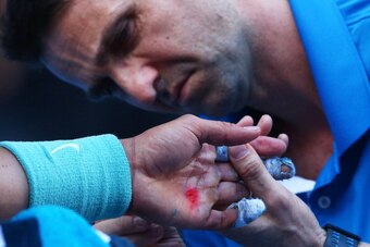 MELBOURNE, AUSTRALIA - JANUARY 22:  A trainer treats the blister on the hand of Rafael Nadal of Spain in his quarterfinal match against Grigor Dimitrov of Bulgaria during day 10 of the 2014 Australian Open at Melbourne Park on January 22, 2014 in Melbourn