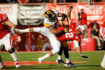 LINCOLN, NE - NOVEMBER 29: Quarterback Ron Kellogg III #12 of the Nebraska Cornhuskers takes a hit from linebacker Christian Kirksey #20 of the Iowa Hawkeyes during their game at Memorial stadium on November 29, 2013 in Lincoln, Nebraska. (Photo by Eric F