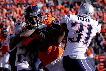 DENVER, CO - JANUARY 19:  Julius Thomas #80 of the Denver Broncos makes a catch as he gets tackled by Kyle Arrington #25 and Aqib Talib #31 of the New England Patriots  during the AFC Championship game at Sports Authority Field at Mile High on January 19,