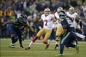 Jan 19, 2014; Seattle, WA, USA; San Francisco 49ers quarterback Colin Kaepernick (7) throws a touchdown pass in the third quarter pressured by Seattle Seahawks defensive end Michael Bennett (72) and linebacker Bruce Irvin (51) during the second half of th