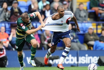 BOLTON, ENGLAND - AUGUST 24:  David Ngog of Bolton Wanderers is pulled back by his shirt by Clint Hill of Queens Park Rangers during the Sky Bet Championship match between Bolton Wanderers and Queens Park Rangers at Reebok Stadium on August 24, 2013 in Bo