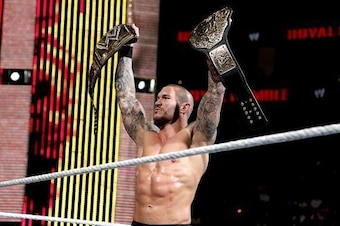 Randy Orton holds up two WWE titles.