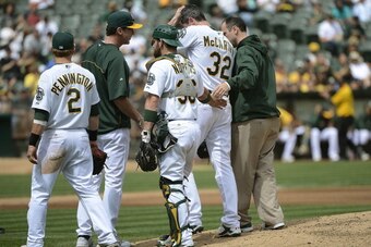 OAKLAND, CA - SEPTEMBER 05:  Brandon McCarthy #32 of the Oakland Athletics is taken out of the game by trainer Nick Paparesta (R) and manager Bob Melvin (2nd L) after McCarthy was hit in the head with a line drive off the bat of Erick Aybar #2 of the Los 