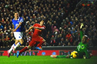 LIVERPOOL, ENGLAND - JANUARY 28:  Luis Suarez of Liverpool scores his team's fourth goal past goalkeeper Tim Howard of Everton as Phil Jagielka of Everton closes in during the Barclays Premier League match between Liverpool and Everton at Anfield on Janua