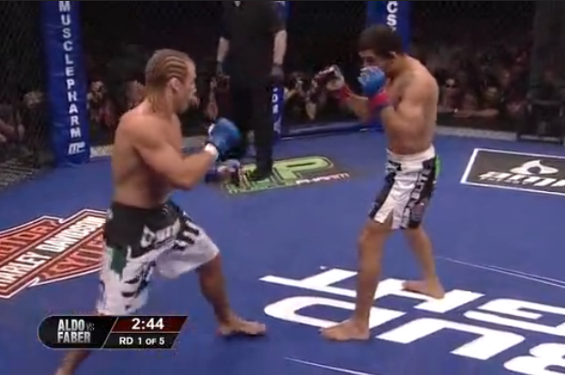 Faber can't shoot from here, and will have to lunge in wild to land his right. Aldo can reach that lead leg with ease though.