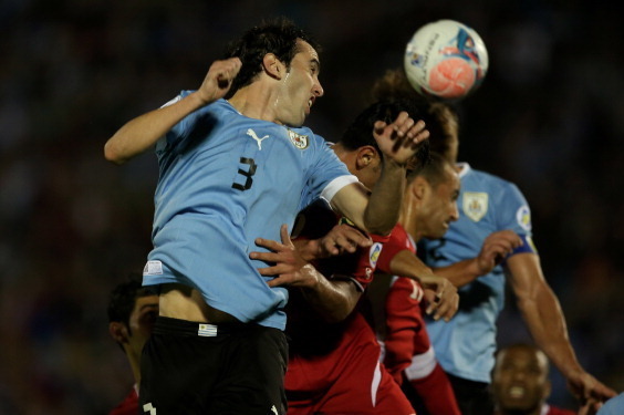 MONTEVIDEO, URUGUAY - NOVEMBER 20:  Diego Godin of Uruguay fights for the ball with Tareq Khattab of Jordan during leg 2 of the FIFA World Cup Qualifier match between Uruguay and Jordan at Centenario Stadium Stadium on November 20, 2013 in Montevideo, Uru