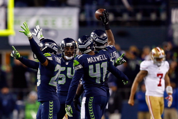 SEATTLE, WA - JANUARY 19:  Strong safety Kam Chancellor #31 of the Seattle Seahawks celebrates after an interception in the fourth quarter as quarterback Colin Kaepernick #7 of the San Francisco 49ers walks by during the 2014 NFC Championship at CenturyLi