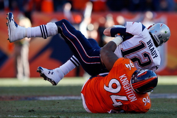 DENVER, CO - JANUARY 19:  Tom Brady #12 of the New England Patriots is sacked by Terrance Knighton #94 of the Denver Broncos on a fourth down in the fourth quarter during the AFC Championship game at Sports Authority Field at Mile High on January 19, 2014