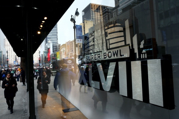 NEW YORK, NY - JANUARY 31:  Fans walk past signage on Super Bowl Boulevard in Times Square prior to Super Bowl XLVIII on January 31, 2014 in New York City. Super Bowl XLVIII will be played between the Seattle Seahawks and the Denver Broncos on February 2,