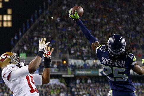 SEATTLE, WA - JANUARY 19:  Cornerback Richard Sherman #25 of the Seattle Seahawks tips the ball up in the air as outside linebacker Malcolm Smith #53 catches it to clinch the victory for the Seahawks against the San Francisco 49ers during the 2014 NFC Cha