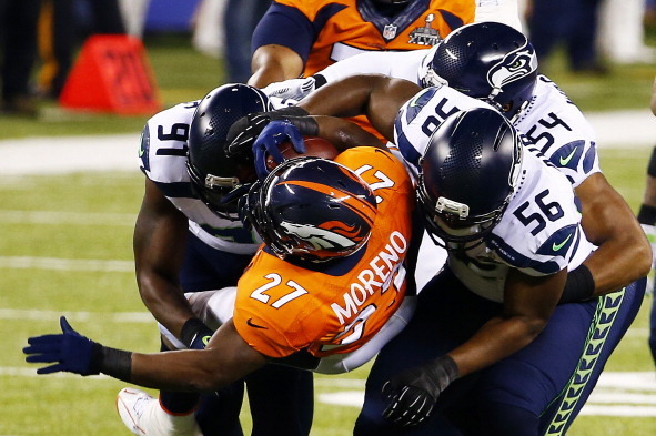 EAST RUTHERFORD, NJ - FEBRUARY 02:  Running back Knowshon Moreno #27 of the Denver Broncos is tackled by defensive end Cliff Avril #56 middle linebacker Bobby Wagner #54 and defensive end Chris Clemons #91 of the Seattle Seahawks in the first quarter of S