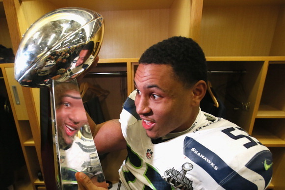 EAST RUTHERFORD, NJ - FEBRUARY 02:  Linebacker Malcolm Smith #53 of the Seattle Seahawks celebrates with the Vince Lombardi Trophy after in the locker room after the 43-8 victory over the Denver Broncos during Super Bowl XLVIII at MetLife Stadium on Febru