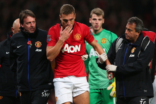 MANCHESTER, ENGLAND - NOVEMBER 10:  Nemanja Vidic of Manchester United is helped from the pitch after sustaining an injury during the Barclays Premier League match between Manchester United and Arsenal at Old Trafford on November 10, 2013 in Manchester, E