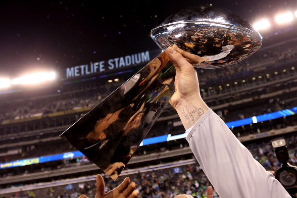 EAST RUTHERFORD, NJ - FEBRUARY 02:  A Seattle Seahawk holds up the Vince Lombardi Trophy after their 43-8 win over the Denver Broncos during Super Bowl XLVIII at MetLife Stadium on February 2, 2014 in East Rutherford, New Jersey.  (Photo by Jeff Gross/Get