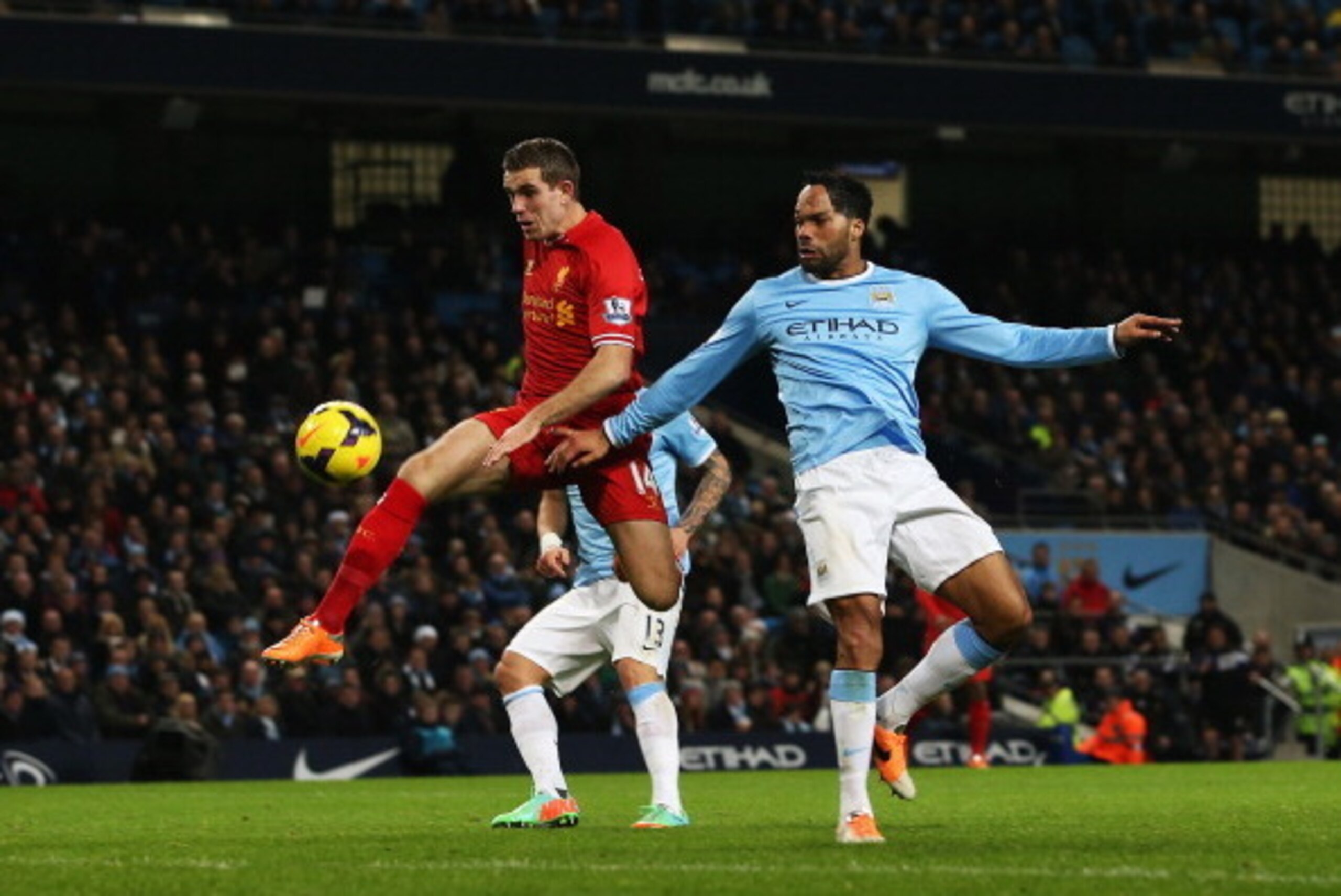 MANCHESTER, ENGLAND - DECEMBER 26:  Jordan Henderson of Liverpool is challenged by Joleon Lescott of Manchester City as he shoots from close range during the Barclays Premier League match between Manchester City and Liverpool at Etihad Stadium on December