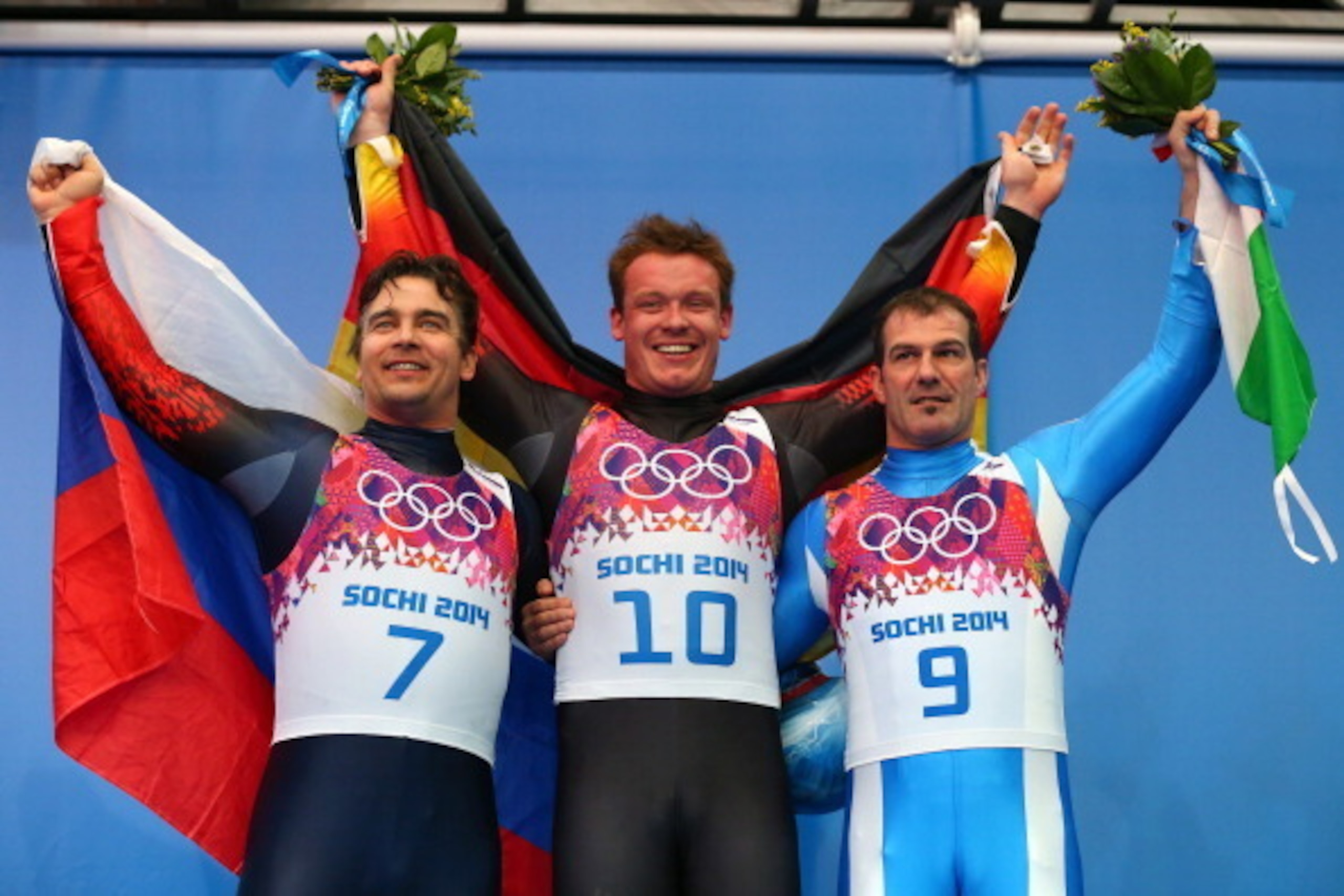 SOCHI, RUSSIA - FEBRUARY 09:  (L-R) Silver medalist Albert Demchenko of Russia, gold medalist Felix Loch of Germany and bronze medalist Armin Zoeggeler of Italy on the podium during the flower ceremony for the Men's Luge Singles on Day 2 of the Sochi 2014