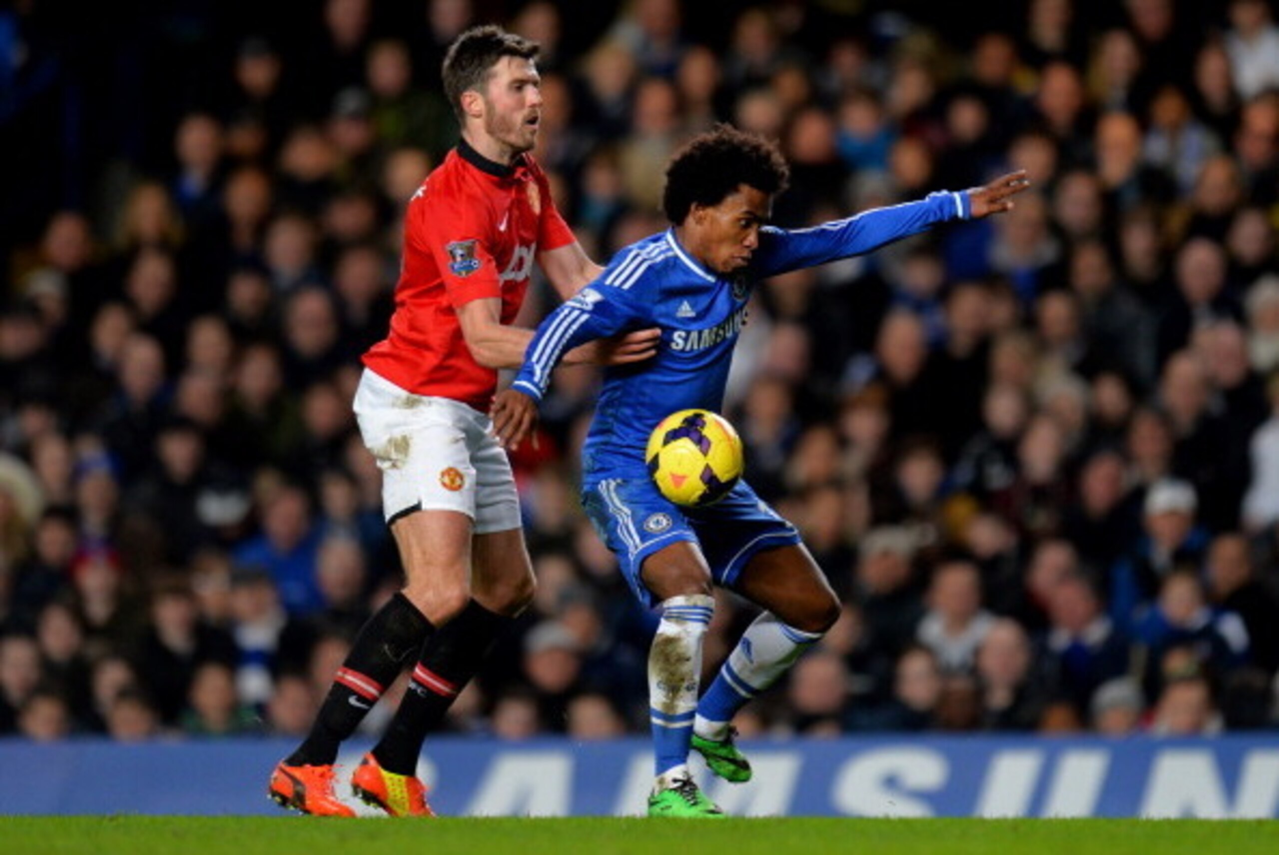 LONDON, ENGLAND - JANUARY 19:  Willian of Chelsea holds off the challenge from Michael Carrick of Manchester United during the Barclays Premier League match between Chelsea and Manchester United at Stamford Bridge on January 19, 2014 in London, England.  