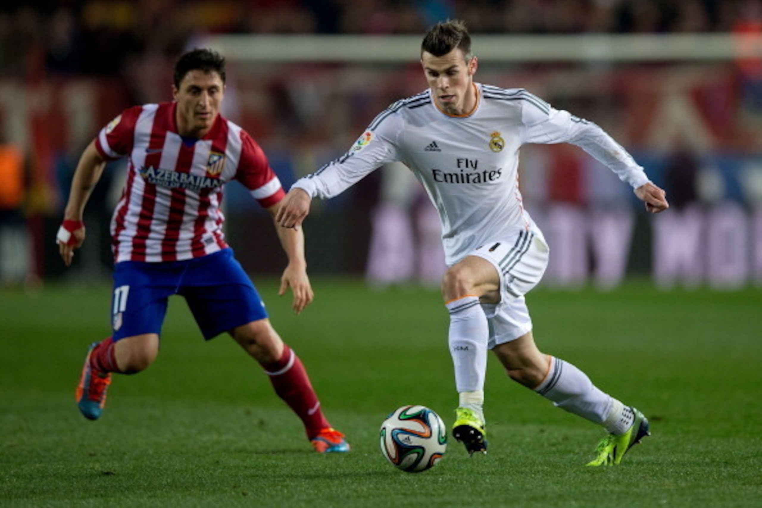 MADRID, SPAIN - FEBRUARY 11: Gareth Bale (R) of Real Madrid CF competes for the ball with Cristian Rodriguez alias El Cebolla (L) of Atletico de Madrid during the Copa del Rey semi-final second leg match between Club Atletico de Madrid and Real Madrid CF 