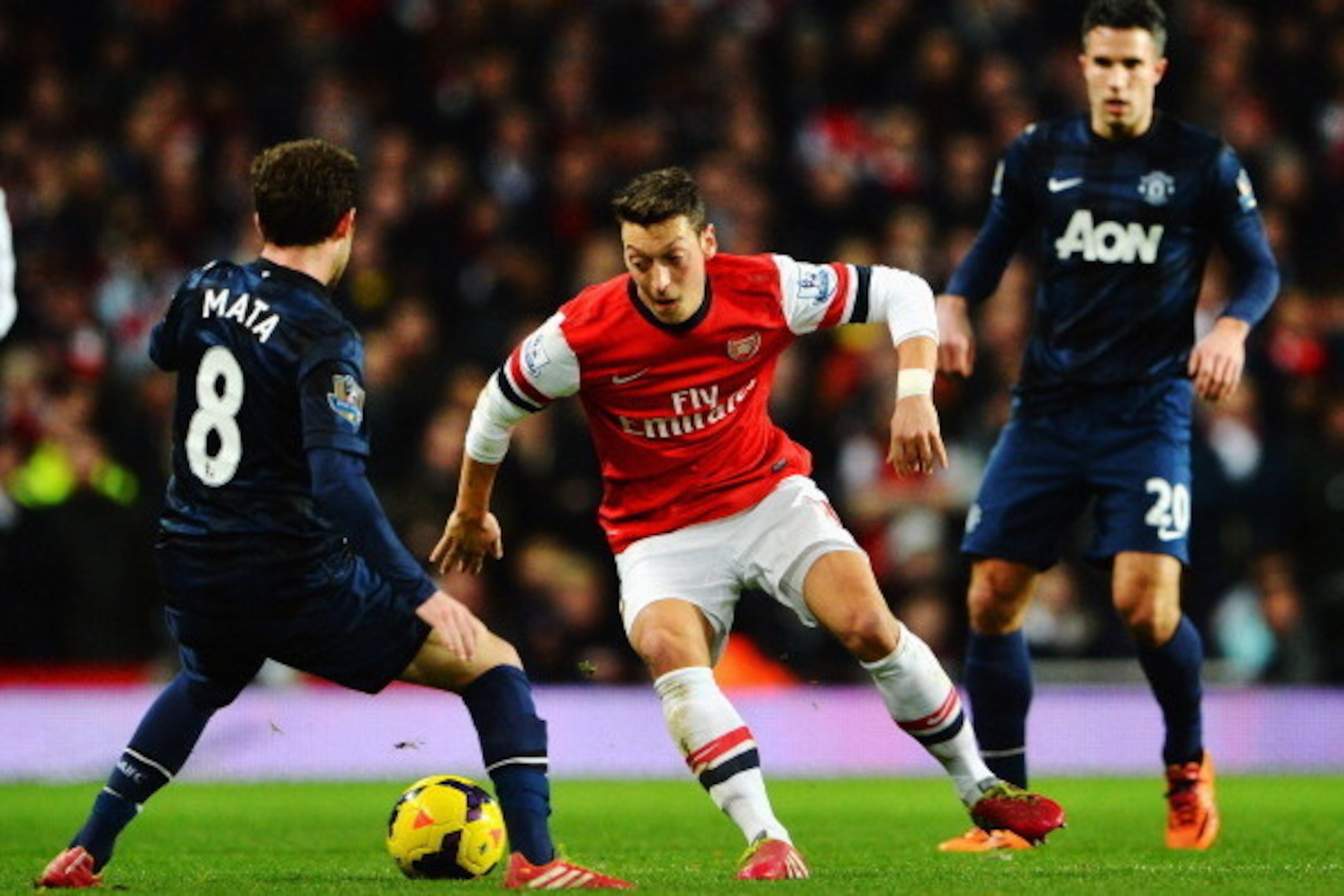 LONDON, ENGLAND - FEBRUARY 12: Mesut Ozil (C) of Arsenal takes on Juan Mata (L) of Manchester United during the Barclays Premier League match between Arsenal and Manchester United at the Emirates Stadium on February 12, 2014 in London, England. (Photo b LONDON, ENGLAND - FEBRUARY 12: Mesut Ozil (C) of Arsenal takes on Juan Mata (L) of Manchester United during the Barclays Premier League match between Arsenal and Manchester United at the Emirates Stadium on February 12, 2014 in London, England. (Photo b