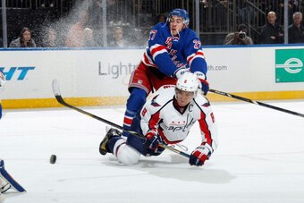 NEW YORK, NY - DECEMBER 08:  Alex Ovechkin #8 of the Washington Capitals shoots the puck as he gets knocked down by Ryan McDonagh #27 of the New York Rangers at Madison Square Garden on December 8, 2013 in New York City. (Photo by Scott Levy/NHLI via Gett