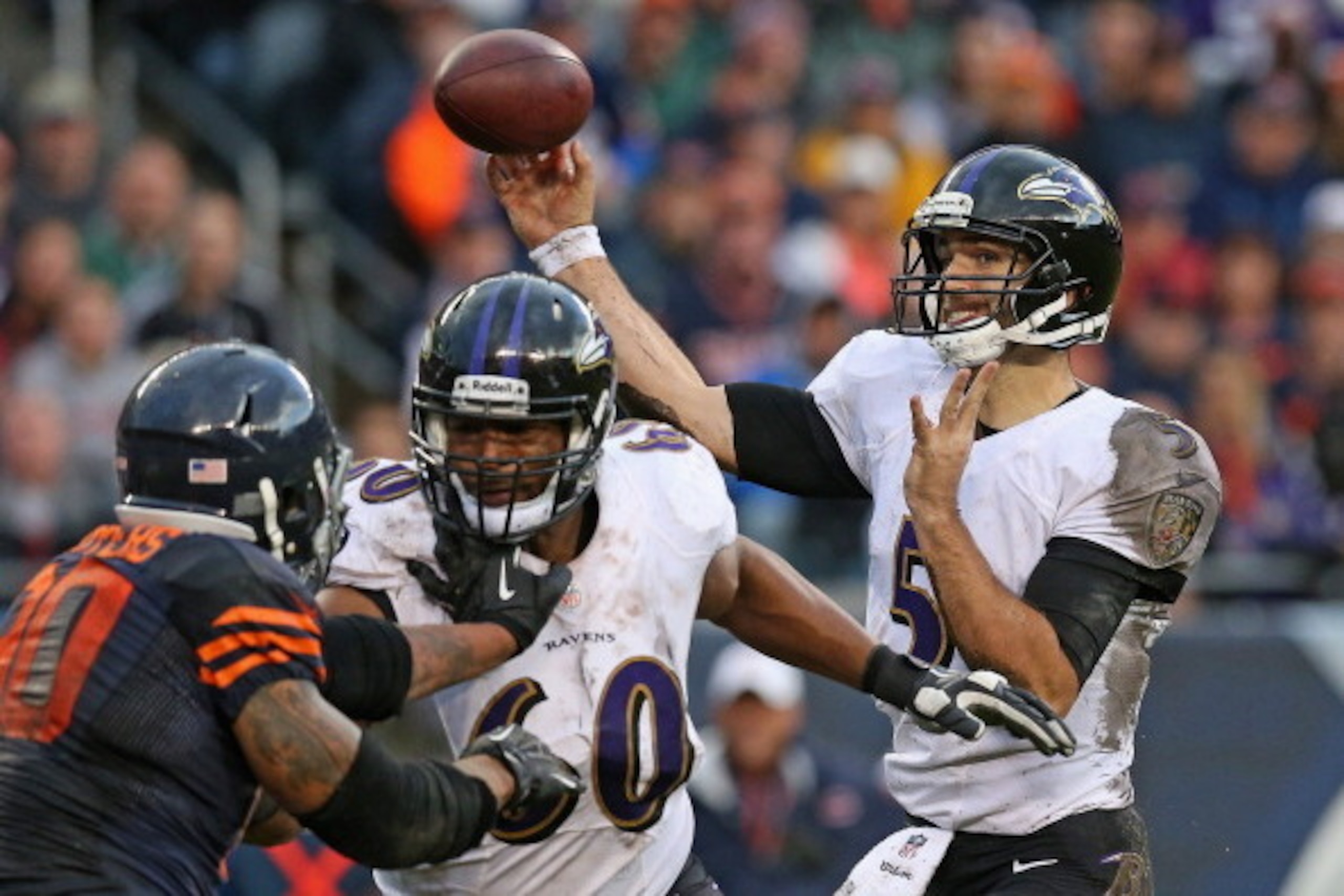 CHICAGO, IL - NOVEMBER 17:  Joe Flacco #5 of the Baltimore Ravens passes as Eugene Monroe #60 blocks Julius Peppers #90 of the Chicago Bears at Soldier Field on November 17, 2013 in Chicago, Illinois. The Bears defeated the Ravens 23-20 in overtime.  (Pho