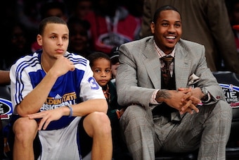 LOS ANGELES, CA - FEBRUARY 18:  Stephen Curry #30 of the Golden State Warriors and the Sophomore Team sits next to Carmelo Anthony of the Denver Nuggets as his son Kiyan Carmelo Anthony is between them during the T-Mobile Rookie Challenge and Youth Jam at
