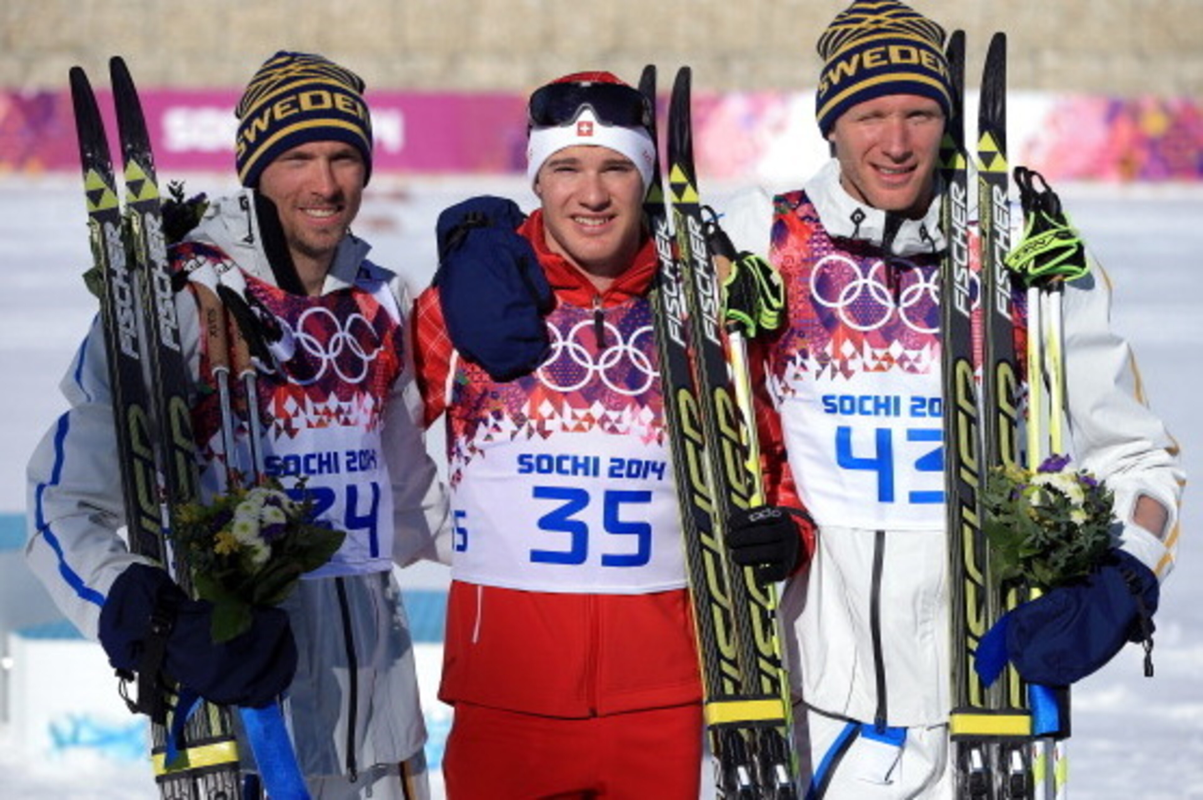 SOCHI, RUSSIA - FEBRUARY 14:  (L-R) Silver medalist Johan Olsson of Sweden, gold medalist Dario Cologna of Switzerland and bronze medalist Daniel Richardsson of Sweden on the podium during the flower ceremony for the Cross Country Men's 15km Classic event