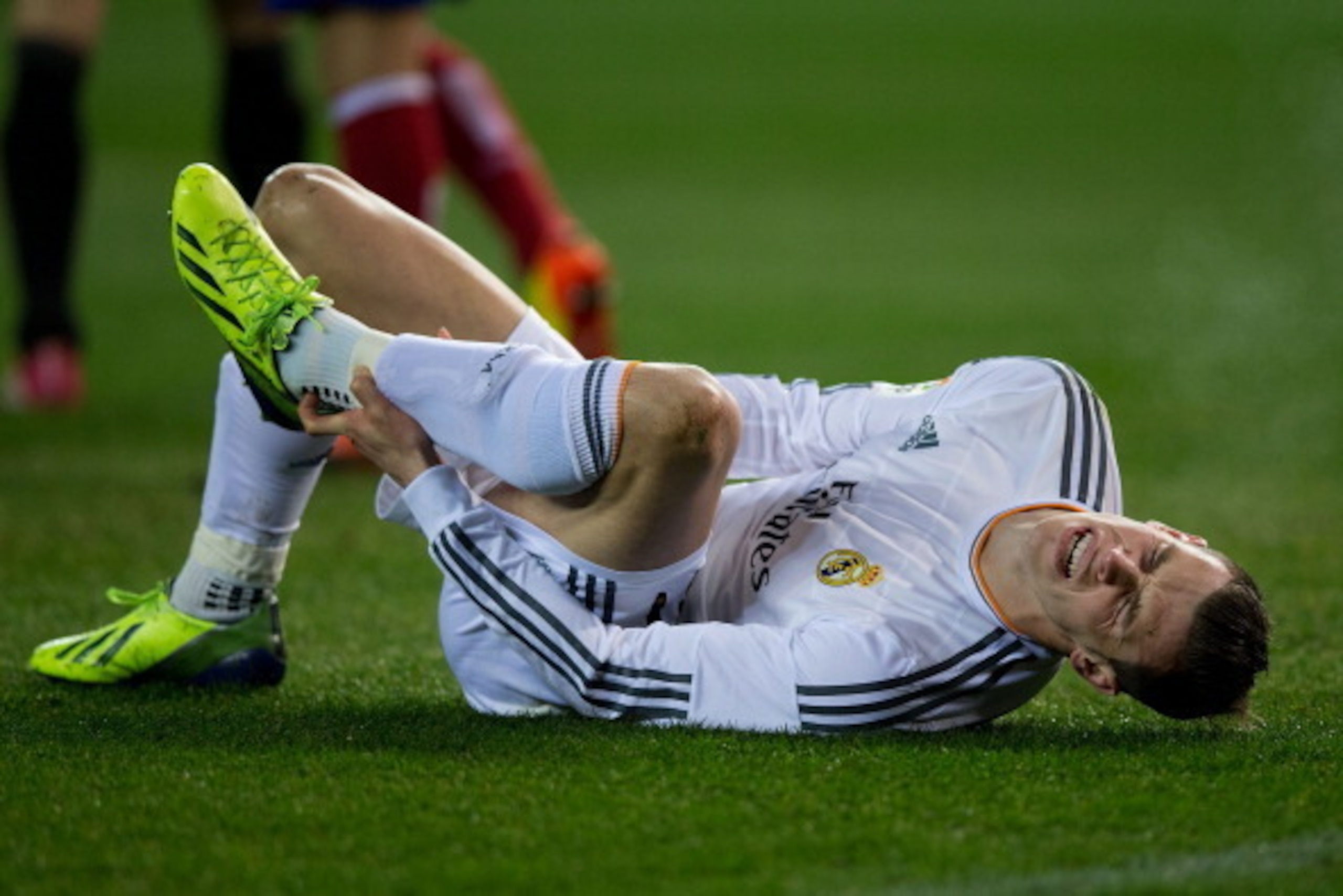 MADRID, SPAIN - FEBRUARY 11:  Gareth Bale of Real Madrid CF grimaces in pain after being tackled by Emiliano Insua of Atletico de Madrid during the Copa del Rey semi-final second leg match between Club Atletico de Madrid and Real Madrid CF at Vicente Cald