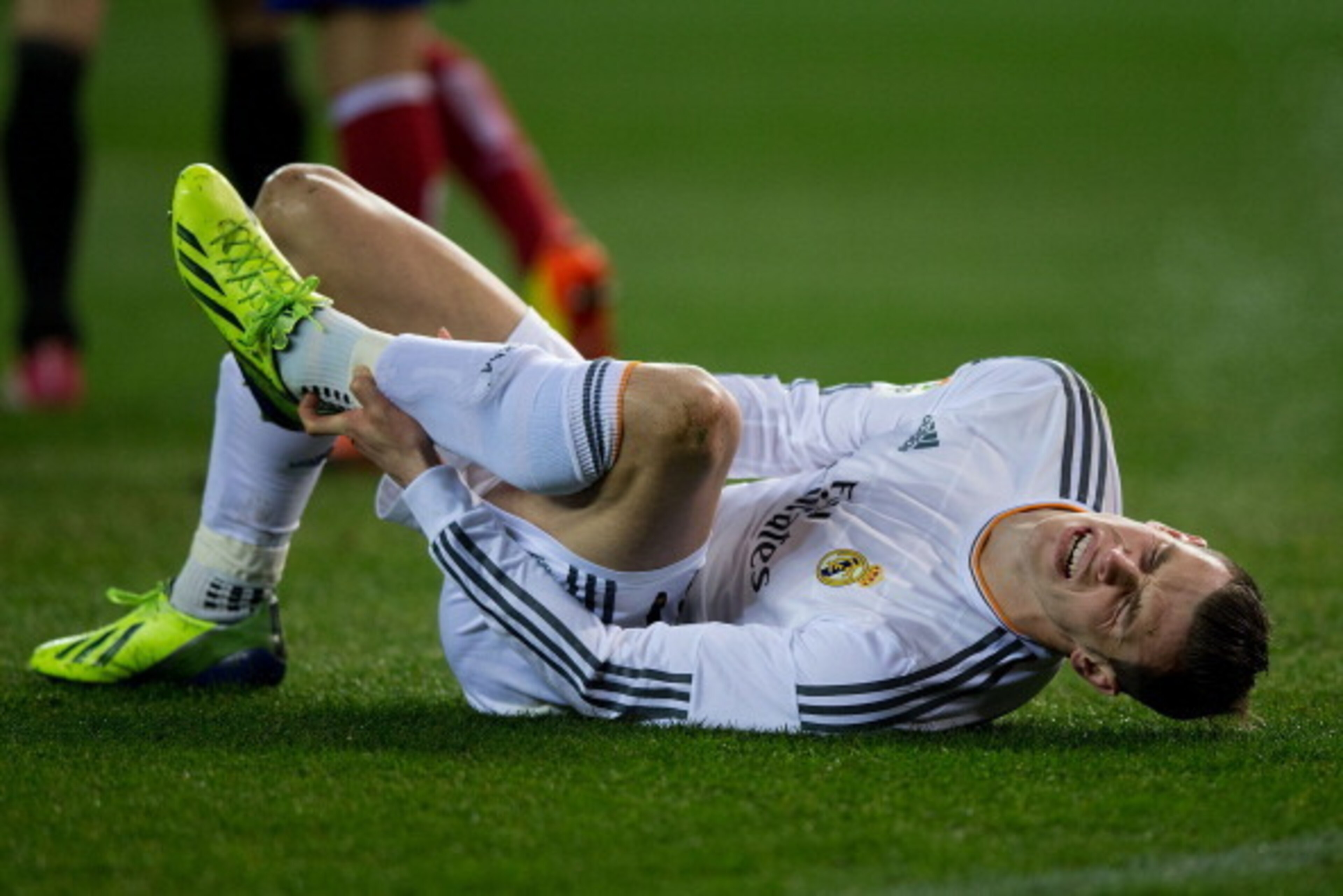 MADRID, SPAIN - FEBRUARY 11:  Gareth Bale of Real Madrid CF grimaces in pain after being tackled by Emiliano Insua of Atletico de Madrid during the Copa del Rey semi-final second leg match between Club Atletico de Madrid and Real Madrid CF at Vicente Cald