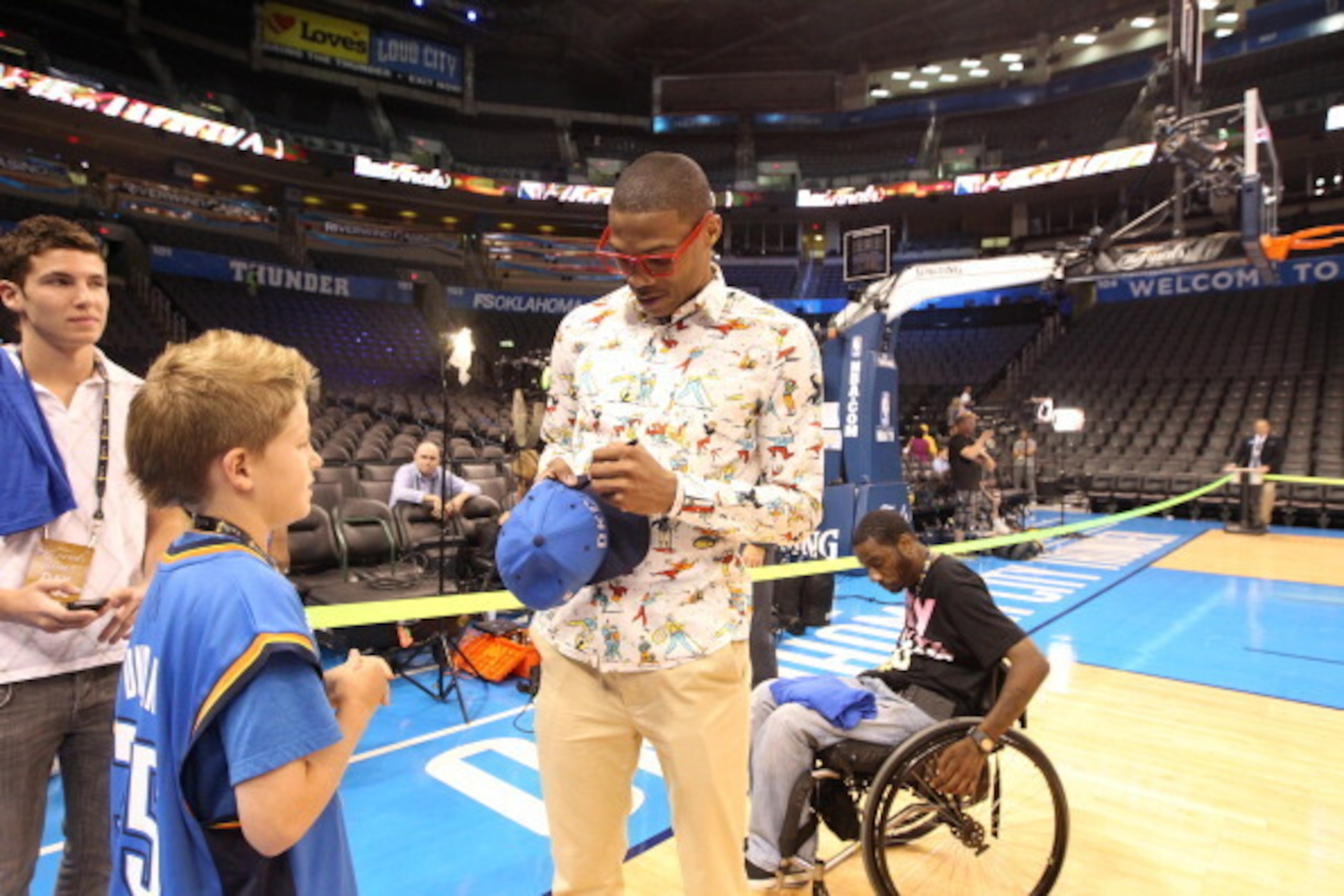 OKLAHOMA CITY, OK - JUNE 12: Russell Westbrook #0 of the Oklahoma City Thunder signs a hat for a young fan prior to the start against the Miami Heat in Game One of the 2012 NBA Finals at Chesapeake Energy Arena on June 12, 2012 in Oklahoma City, Oklahoma.