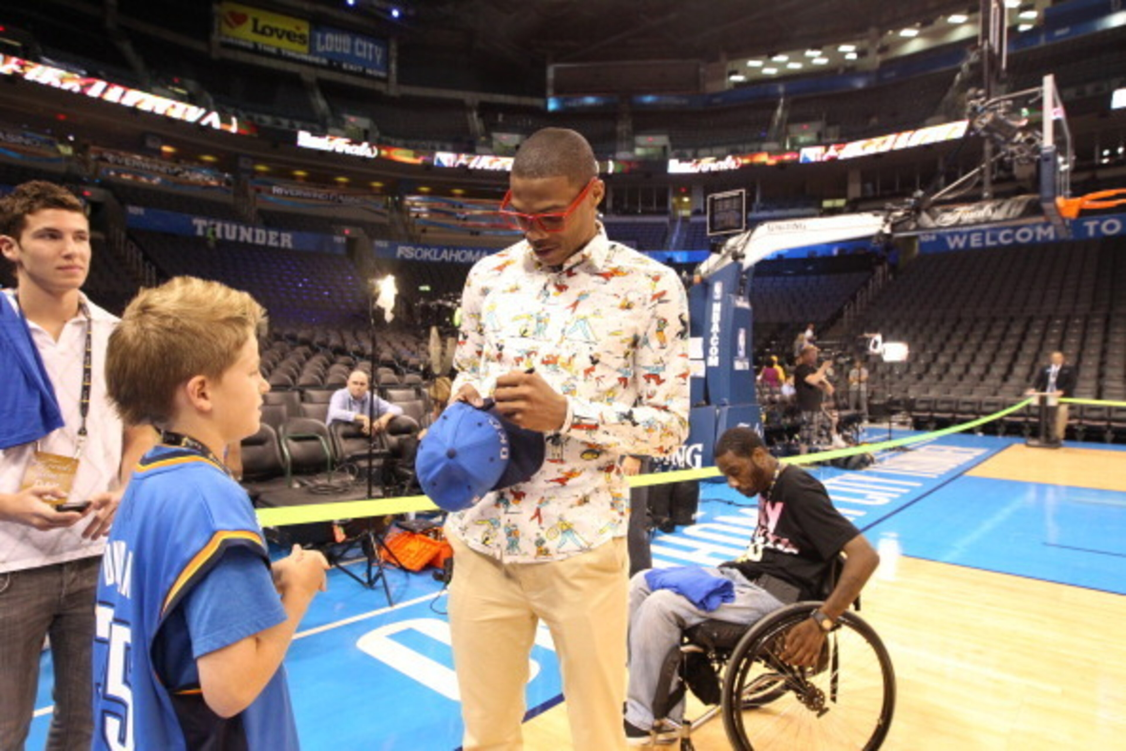 OKLAHOMA CITY, OK - JUNE 12: Russell Westbrook #0 of the Oklahoma City Thunder signs a hat for a young fan prior to the start against the Miami Heat in Game One of the 2012 NBA Finals at Chesapeake Energy Arena on June 12, 2012 in Oklahoma City, Oklahoma.