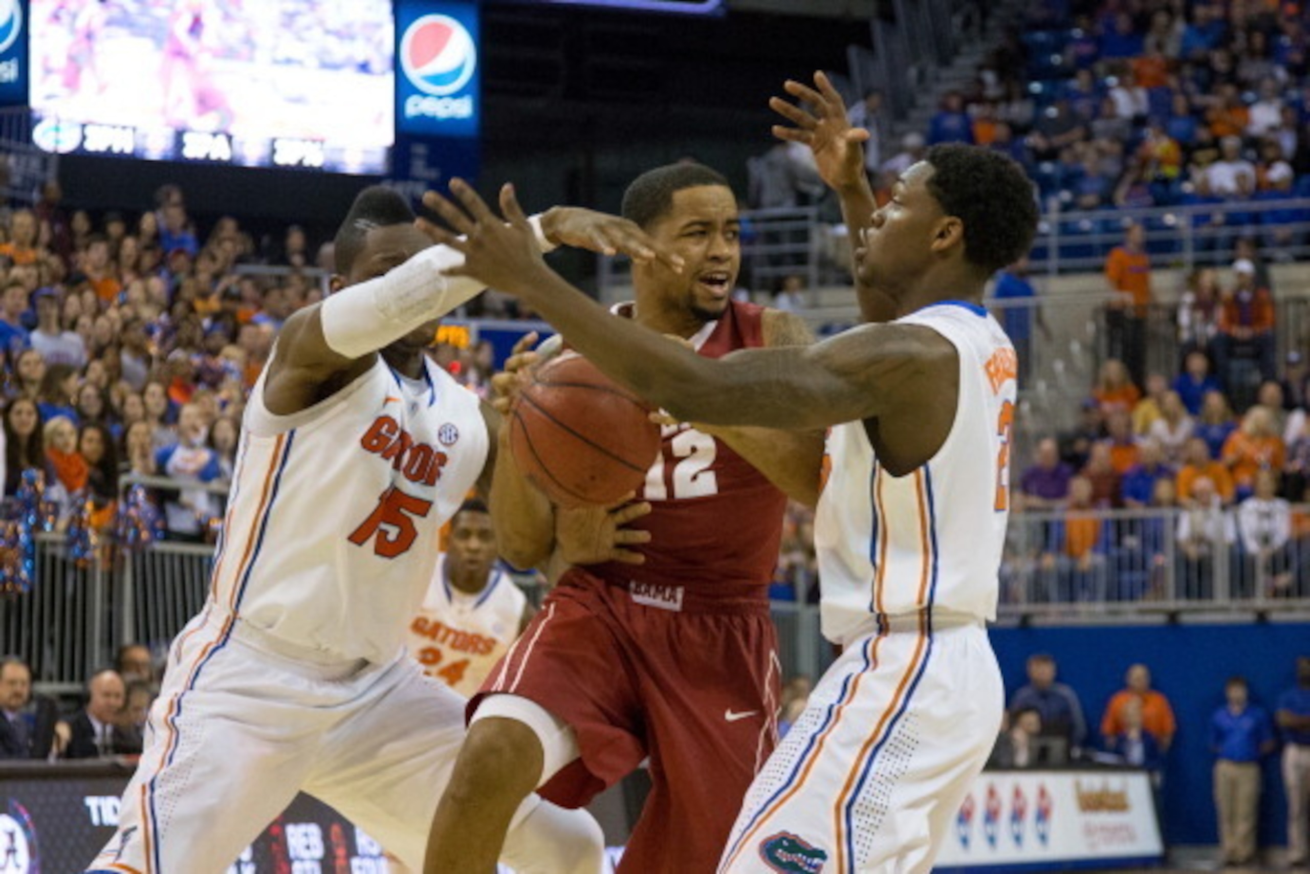 GAINESVILLE, FL - FEBRUARY 08: Trevor Releford #12 of the Alabama Crimson Tide is defended by Michael Frazier II #20 of the Florida Gators as Will Yeguete #15 knocks the ball loose during the first half of the game at the Stephen C. O'Connell Center on Fe
