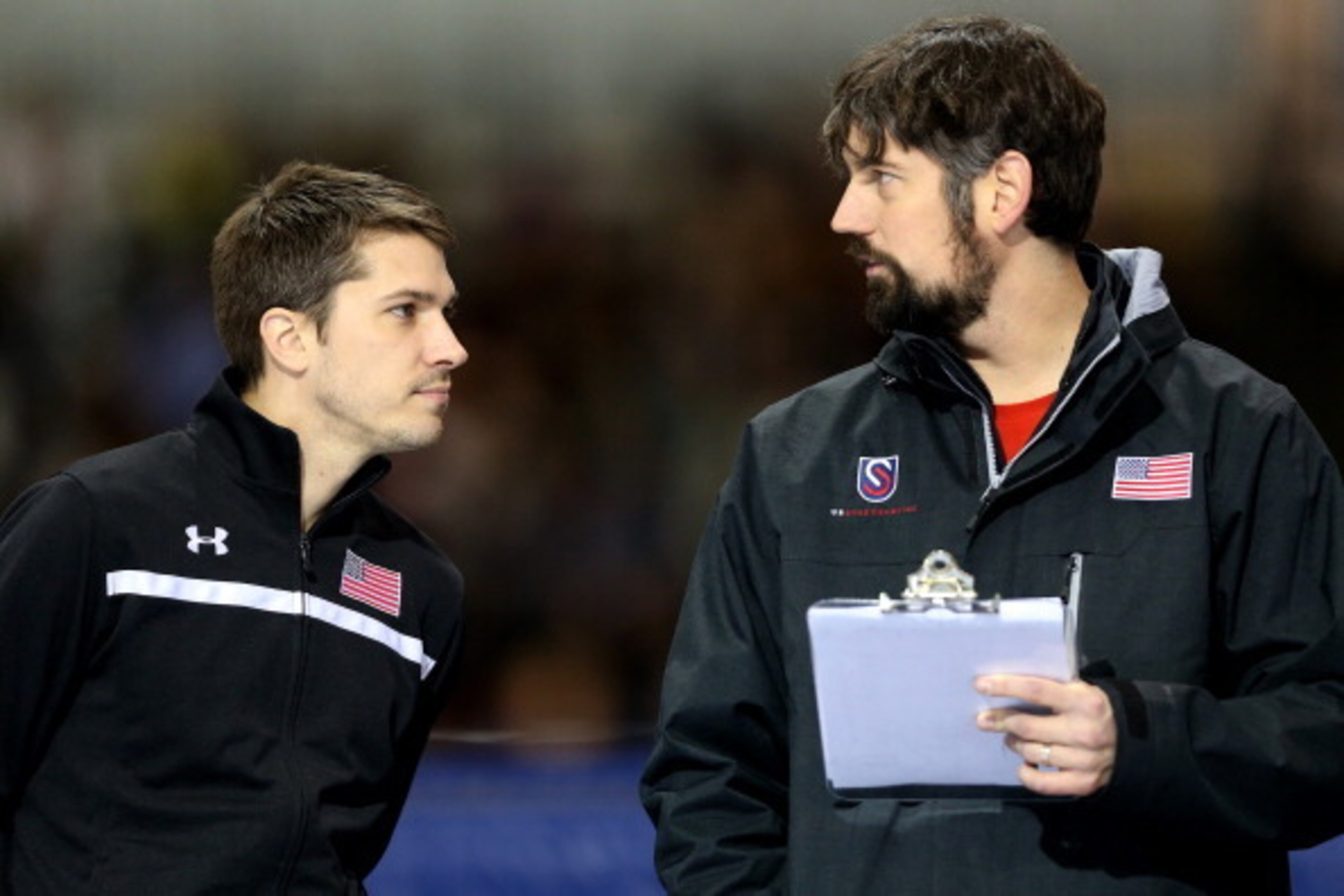 SALT LAKE CITY, UT - DECEMBER 28:  Kip Carpenter, national all around head coach, confers with Matt Kooreman, national training center coach, on the sidelines duirng the men's 500 meter during the U.S. Speed Skating Long Track Olympic Trials at the Utah O