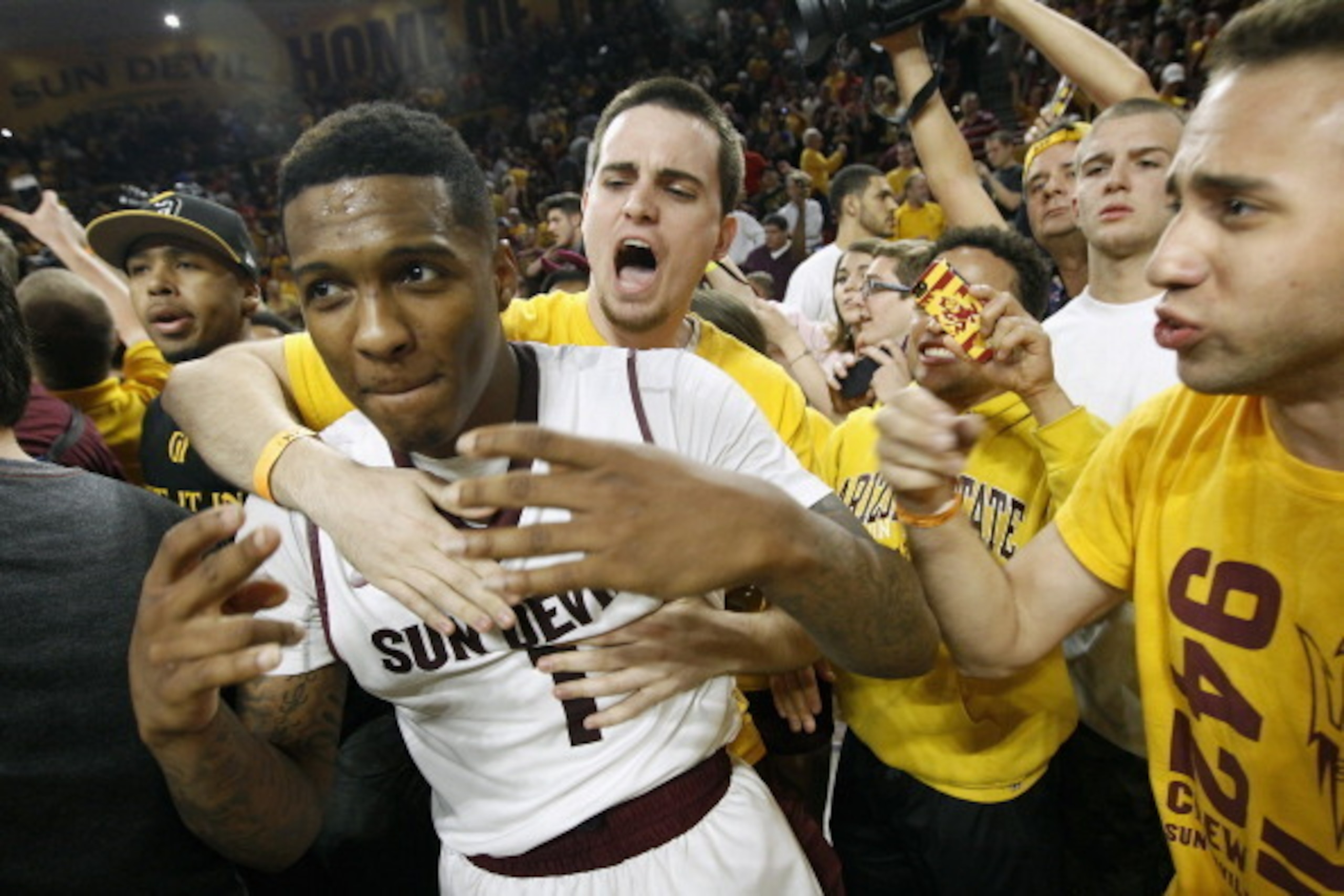 TEMPE, AZ - FEBRUARY 14:  Jahii Carson #1 of the Arizona State Sun Devils is embraced by students in celebration of a 69-66 double overtime victory over the Arizona Wildcats during a college basketball game at Wells Fargo Arena on February 14, 2014 in Tem