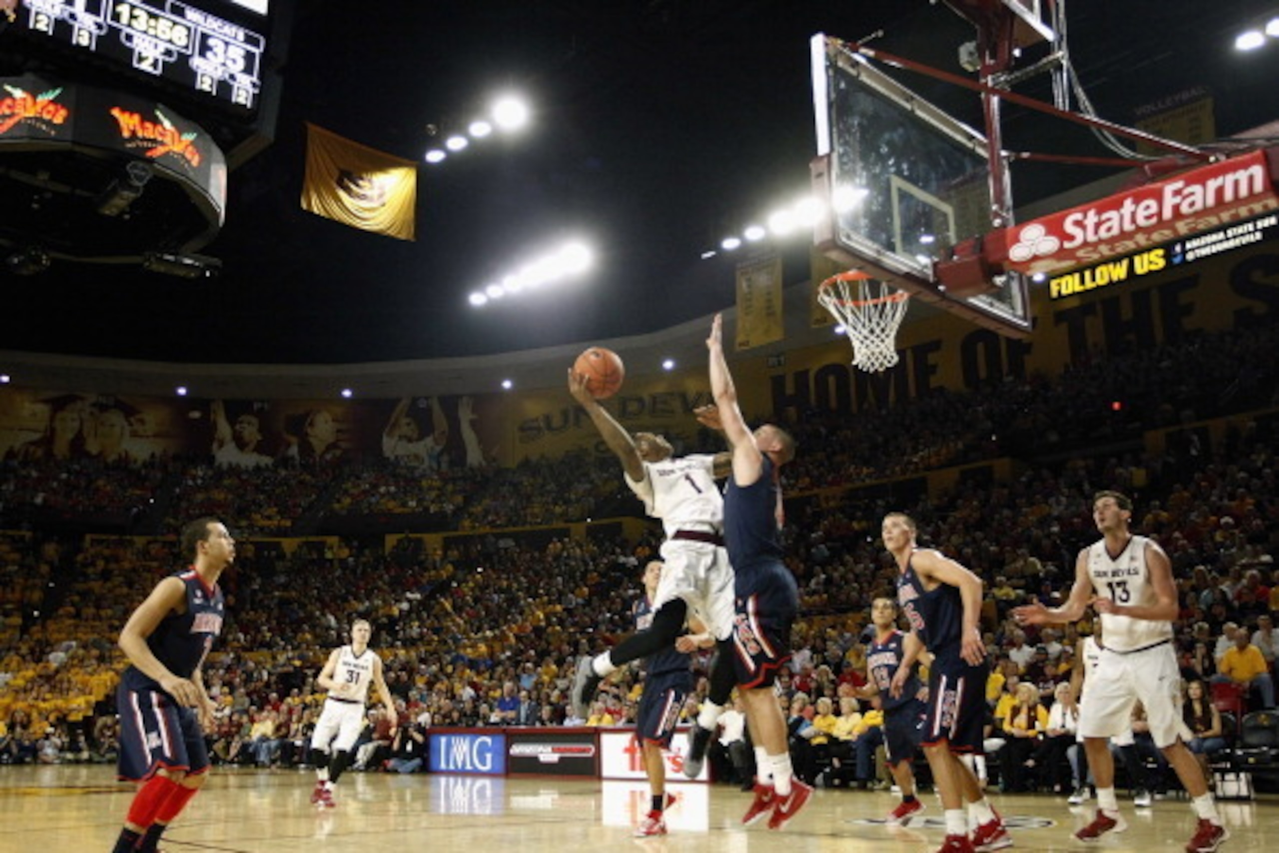 TEMPE, AZ - FEBRUARY 14:  Jahii Carson #1 of the Arizona State Sun Devils drives to the basket as T.J. McConnell #4 of the Arizona Wildcats defends during the first half of a college basketball game at Wells Fargo Arena on February 14, 2014 in Tempe, Ariz