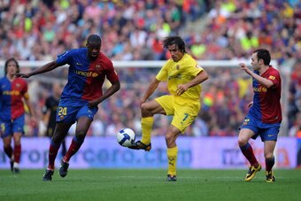 BARCELONA, SPAIN - MAY 10: Robert Pires (C) of Villarreal controls the ball while Toure Yaya (L) and Andres Iniesta of Barcelona close in during the La Liga match between Barcelona and Villarreal at the Nou Camp stadium on May 10, 2009 in Barcelona, Spain