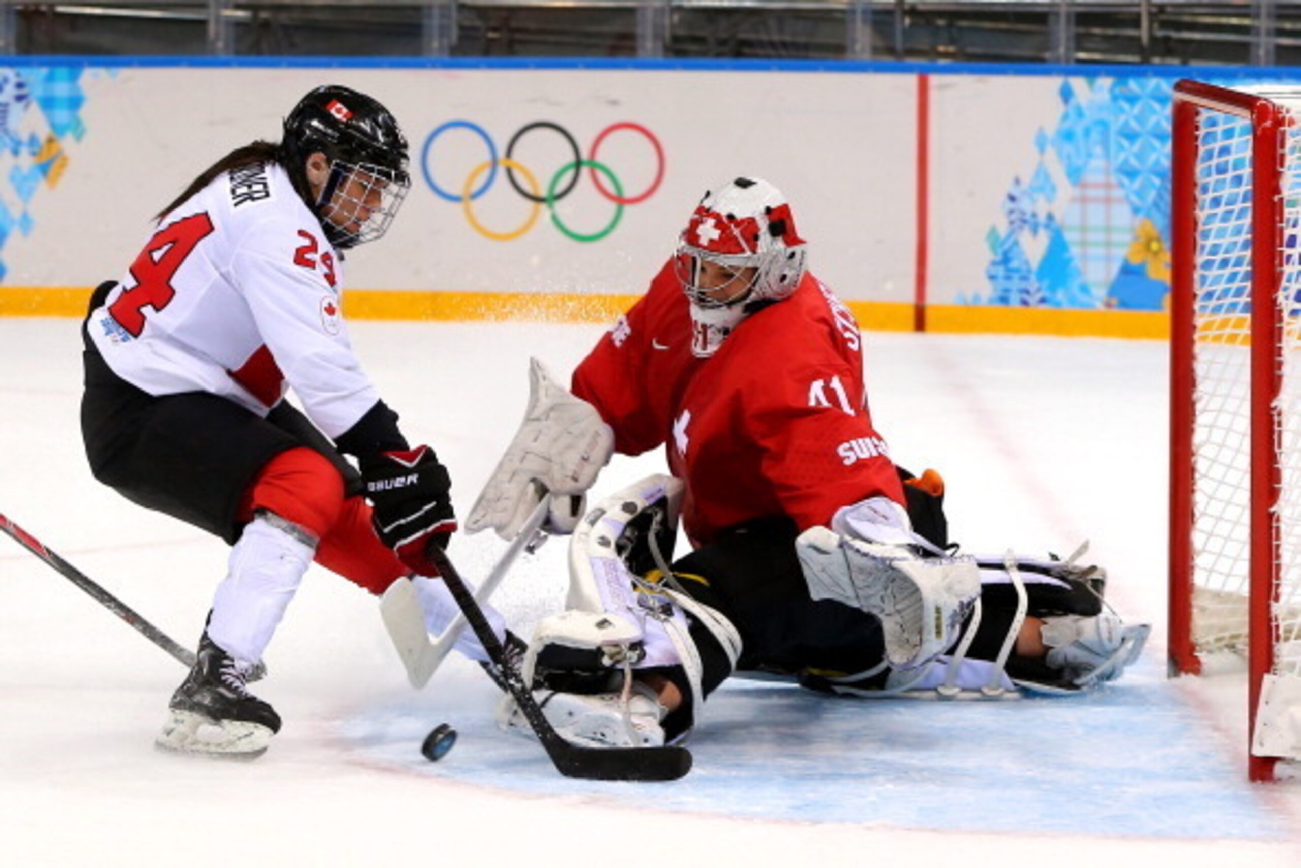 SOCHI, RUSSIA - FEBRUARY 17:  Natalie Spooner #24 of Canada fights for the puck against Florence Schelling #41 of Switzerland during the Women's Ice Hockey Playoffs Semifinal game on day ten of the Sochi 2014 Winter Olympics at Shayba Arena on February 17